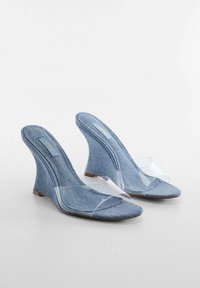 Sandali con zeppa in denim con cinturini trasparenti. Design con punta aperta. Colore azzurro chiaro, tomaia in denim texturizzato e tacco curvo per stabilità.