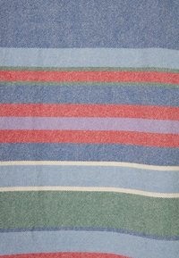 Textiel met horizontale strepen in blauw, rood, groen en lichtpaars, met een gestructureerde weving en variërende dikte in de patronen.