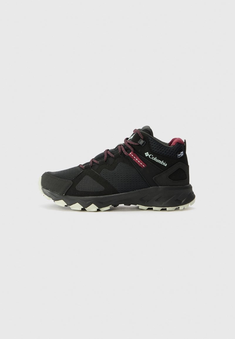 Chaussure de randonnée Columbia noire avec semelle blanche robuste et lacets bordeaux, vue latérale sur fond uni clair.