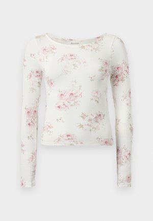 Cămașă albă cu mânecă lungă, cu o textură texturată, având un model floral în nuanțe de roz și bej. Guler rotund și design mulat.