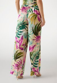 Pantaloni a gamba larga con fantasia floreale realizzati in tessuto leggero, caratterizzati da foglie verdi e fiori rosa su sfondo beige, con vita elastica.