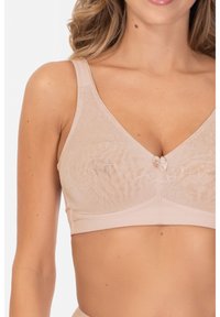 Jasno beżowy stanik o miękkim, teksturowanym wzorze, z dekoltem w kształcie litery v, regulowanymi ramiączkami oraz małym kokardkowym detalem na środku.