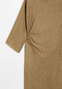 Robe en tissu brun texturé avec des manches trois-quarts et un détail torsadé à la taille, présentant un design ample et minimaliste.