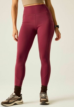 Kobieta nosząca bordo legginsy z wysokim stanem z boczną kieszenią, brązowe skarpetki, buty do biegania i zegarek fitness na lewym nadgarstku.