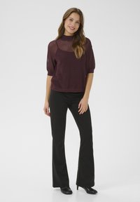 Burgundy textured pullover with short sleeves, paired with black flared trousers and ankle boots, displayed against a plain white background.