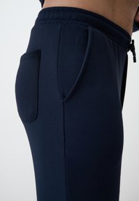 Pantalons de jogging bleu marine en coton doux, avec une poche latérale et une taille élastique avec cordon de serrage pour un ajustement réglable.