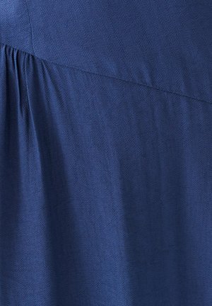 Tela azul oscuro, con una superficie texturizada y detalles de pliegues suaves a lo largo de la costura, creando una apariencia fluida.