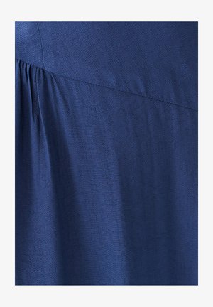 Tumši zili audums ar teksturētu virsmu, uz apakšējās malas ar krokas dizainu. Materiāls izskatās mīksts un plūstošs.