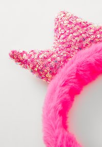 Un bandeau rose avec un bandeau en peluche et un accent en sequins en forme d'étoile. Des sequins roses étincelants couvrent l'étoile, créant un contraste texturé.