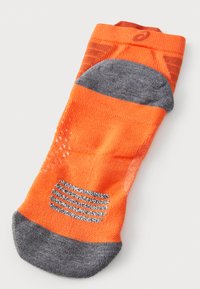 Calcetín deportivo naranja y gris con un diseño texturizado, talón reforzado y líneas de agarre de goma en la suela para una tracción mejorada.