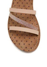 Sandal de color bronce con tres correas: dos planas, en tono nude, y una brillante en plata. La plantilla presenta cuero marrón con un patrón de estrellas. Bordes cosidos.
