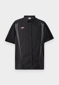 Μαύρο πουκάμισο με κοντά μανίκια και κουμπιά, με γκρι πλαϊνές επιφάνειες και κόκκινο-άσπρο λογότυπο Umbro στο αριστερό στήθος.