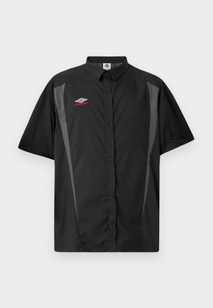 Μαύρο πουκάμισο με κοντά μανίκια και κουμπιά, με γκρι πλαϊνές επιφάνειες και κόκκινο-άσπρο λογότυπο Umbro στο αριστερό στήθος.