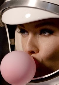 Astronauta w błyszczącej białej hełmie z srebrnymi akcentami. Duża bańka z gumy do żucia w kolorze różowym jest wydmuchana, podkreślając usta i wyraz twarzy podmiotu.