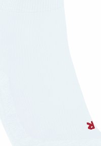 Calzino bianco con texture a coste, con un piccolo logo rosso all'altezza della caviglia. L'attenzione è rivolta al design e al materiale del calzino.