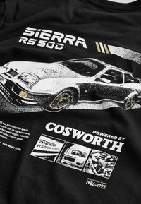Must t-särk valge Ford Sierra RS500 auto graafikaga, tekst "Powered by Cosworth" ja tootmisaastate 1986-1992 detailidega.