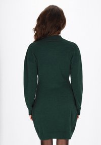 Sukienka z długim rękawem w ciemnozielonym dzianinowym materiale, z wysokim kołnierzem, dopasowanym krojem i teksturowanym wykończeniem.