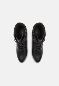 Botine negre din piele, până la gleznă, cu o textură netedă, concepute cu șireturi și fermoare laterale pentru o uzură ușoară. Au un vârf rotunjit.