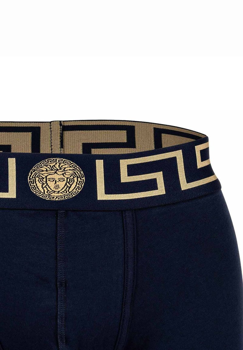 Navy blue boxer briefs with a patterned gold waistband featuring a Greek key design and a central Medusa logo in the front.
