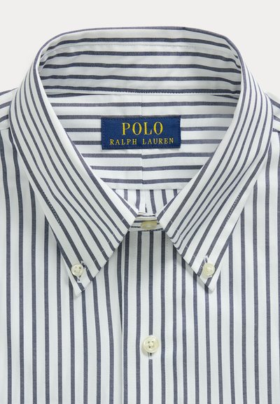 Fehér ing keskeny sötétkék függőleges csíkokkal és Polo Ralph Lauren címkével a gallér belsejében.