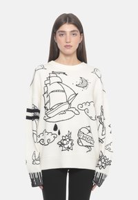 Gestickter Pullover in Creme mit schwarzen maritimen und floralen Mustern, ausgestattet mit einem Rundhalsausschnitt und gestreiften Rippbündchen.