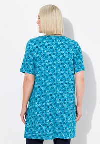Vestito tunica a maniche corte in turchese con un motivo floreale. Tessuto morbido, taglio dritto, che arriva a metà coscia, con scollatura rotonda e spacchi ai lati.