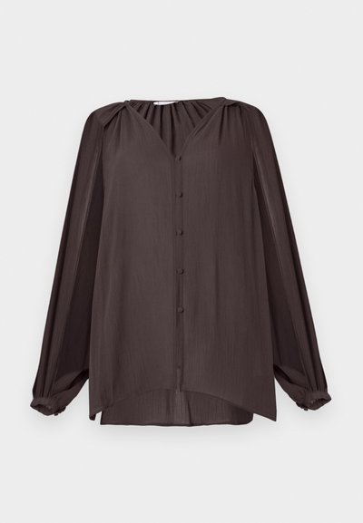 Langärmliges, V-Ausschnitt-Shirt aus glattem, strukturiertem Stoff. Dunkelbraune Farbe mit Knöpfen auf der Vorderseite und gerafftem Schulterdetail, asymmetrischer Saum.