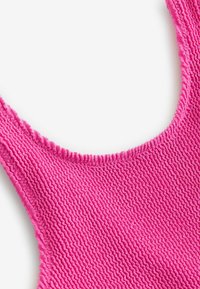 Jasnoróżowy strój typu bodycon z teksturowaną, prążkowaną powierzchnią i zaokrąglonym dekoltem, z elastycznymi krawędziami, które zapewniają dopasowany wygląd.