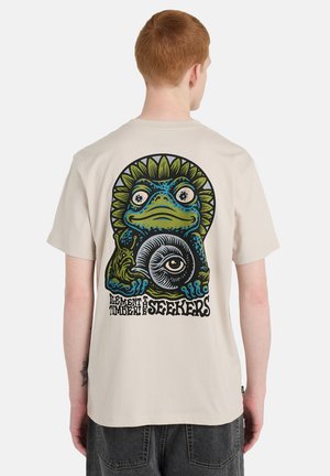Beżowa bawełniana koszulka z kolorową ilustracją żaby z akcentami w formie promieni słonecznych oraz napisem "ELEMENT TIMBER SEEKERS" na plecach.