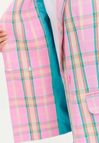 Ružový károvaný blejzer s tyrkysovou podšívkou. Obsahuje dva gombíky, dve predné vrecká a klasický strih. Textúrovaná tkanina s vzorovaným dizajnom.