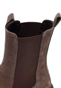 Botín de ante marrón a la altura del tobillo con paneles laterales elásticos y bucles de tirón para poner y quitar fácilmente, con un acabado texturizado y suela duradera.