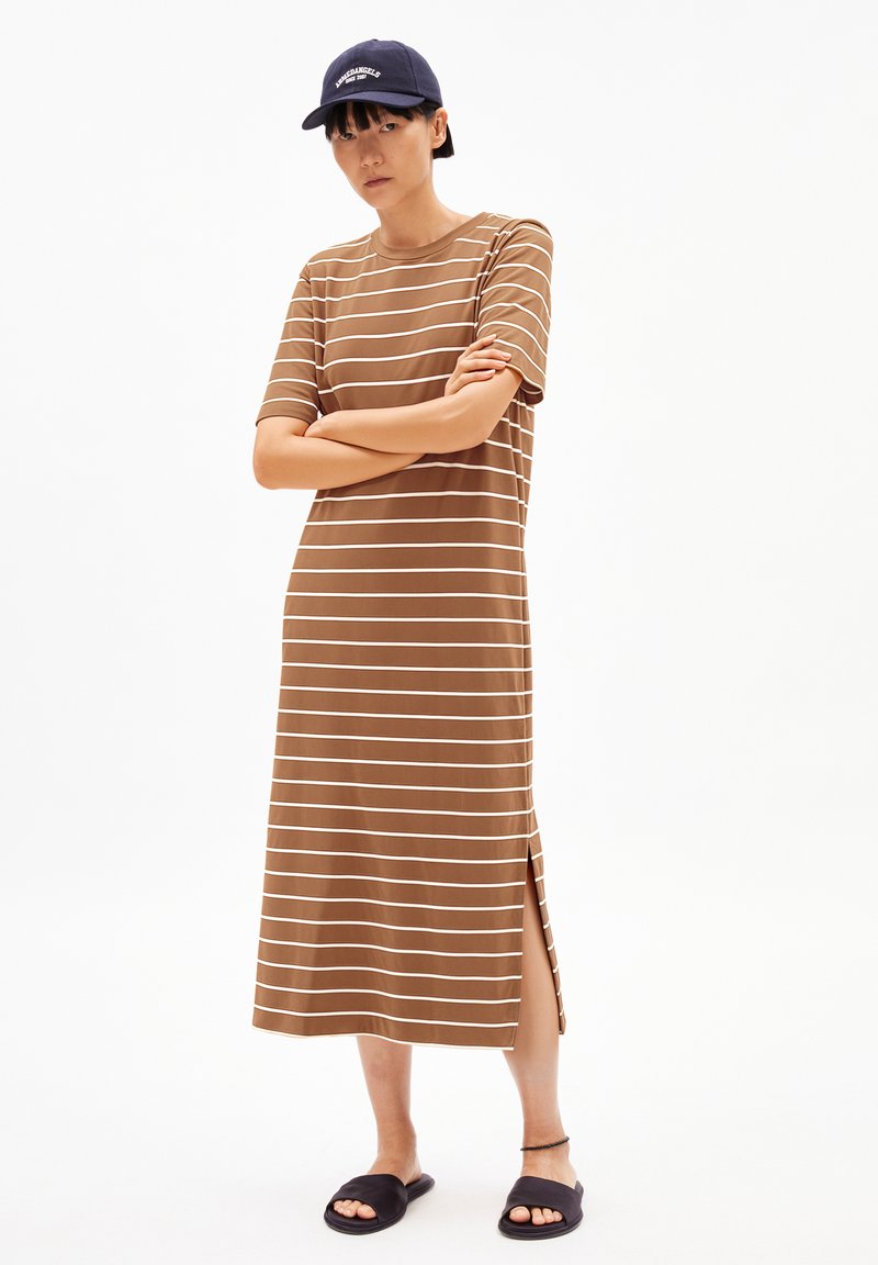 Brown striped midi dress with short sleeves and side slits, paired with a navy cap and black slide sandals. Smooth fabric texture.