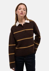 Pull en laine marron avec des rayures jaunes, un col blanc et une patte de boutonnage. Dispose de manches longues et d'une coupe décontractée.