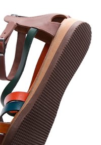 Sandale en cuir avec des brides multicolores et une semelle en caoutchouc brun texturée, vue de côté en angle.