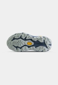 Suola della scarpa in grigio chiaro con un motivo di battistrada profondo, con accenti blu e un logo giallo prominente al centro. Superficie testurizzata per una migliore aderenza.