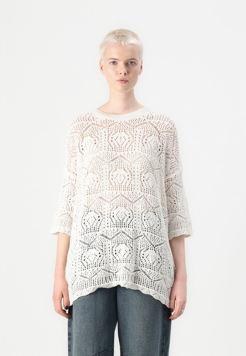Pull blanc en tricot ouvert avec un motif géométrique, col rond et manches trois-quarts. Tissu léger et finition texturée.