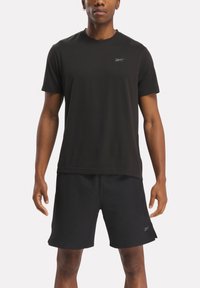 Sort atletisk t-shirt med korte ærmer og rund halsudskæring, parret med sorte shorts. Har et diskret logo på brystet.