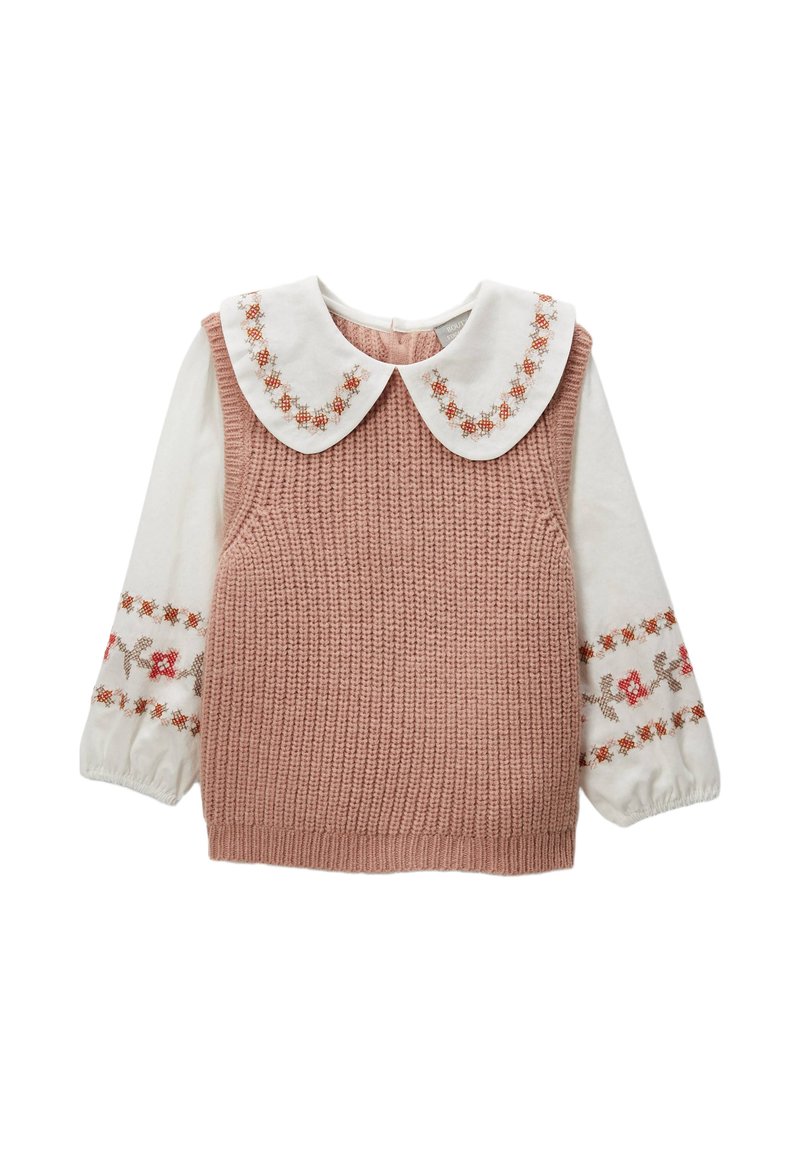 Haut sans manches en tricot rose avec une chemise blanche en dessous. Le col est orné de broderies florales ; les manches sont bouffantes avec des accents décoratifs.