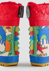 Bunte wasserdichte Stiefel haben ein rotes gesteppte Obermaterial, einen grün-blauen strukturierten Körper mit Dinosauriermustern und eine Gummisohle mit gelben Akzenten.