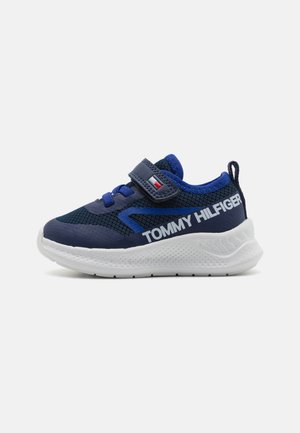 Granatowe dziecięce buty sportowe wykonane z siateczki i materiałów syntetycznych, z białą gumową podeszwą, rzepem oraz brandingiem TOMMY HILFIGER.