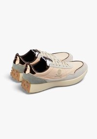 Par de zapatillas beige con detalles en ante gris, cordones blancos, logo de calavera y huesos cruzados en los costados y talones con suela de goma texturizada.