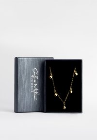 Guldkæde med fem sphæriske charms, præsenteret i en struktureret sort æske. Kæden har en sart kæde og en poleret finish.
