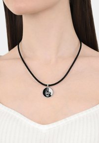 Collana in corda nera intrecciata con un pendente circolare in argento che presenta un design a rilievo di uno scorpione. Il pendente ha una finitura lucida.