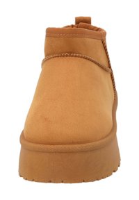 Stivaletti alla caviglia in pelle scamosciata color cuoio con punta rotonda, dettagli cuciti e suola in gomma. Dotati di un passante posteriore per un facile indosso.