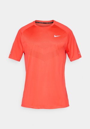 Rotes sportliches T-Shirt aus leichtem Stoff. Verfügt über ein strukturiertes Muster auf der Brust und einen Rundhalsausschnitt. Kleines weißes Logo auf der Vorderseite.