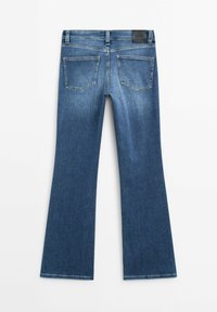 Uppvikta blå jeans med en slät yta, som har en medelhög midja, bakfickor och subtila blekningar längs benen.
