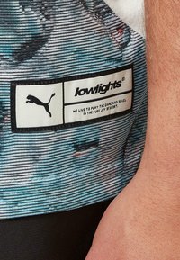 Gemustertes kurzärmliges Hemd mit einem blau-schwarzen Streifenmuster, einem Markenetikett und einer glatten Stoffstruktur.