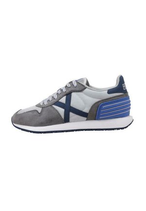 Zapatillas que combinan gamuza gris con detalles azul. El diseño incluye una suela blanca y un detalle en el talón texturizado en azul.