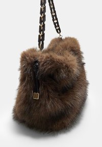 Brun faux fur håndtaske med en rund form, der har et flettet mørkt spænde og hardware i guldtonet på lynlåsen. Tekstur overflade i blød kvalitet.