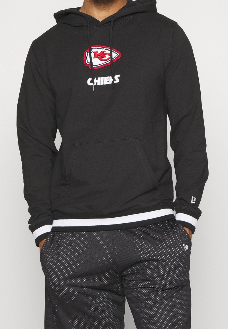 Sweat à capuche noir avec le logo des Kansas City Chiefs en rouge et blanc. Comprend une poche avant, un cordon de serrage à la capuche et des poignets et un ourlet à rayures blanches.